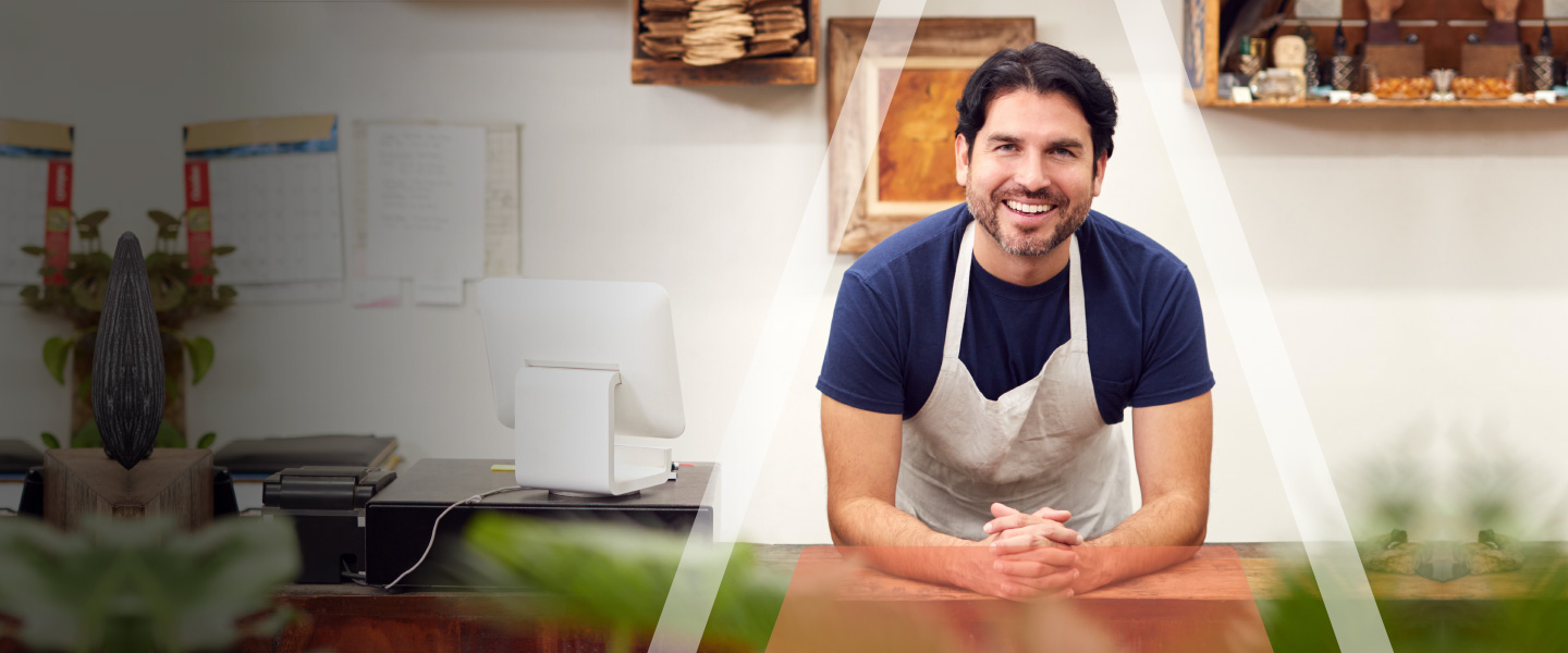 Smiling Man Rests Forearms on Check Out Counter