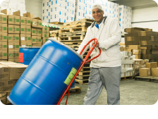Man Moves Blue Barrel in Industrial Facility